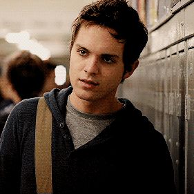 a young man standing next to lockers in a hallway