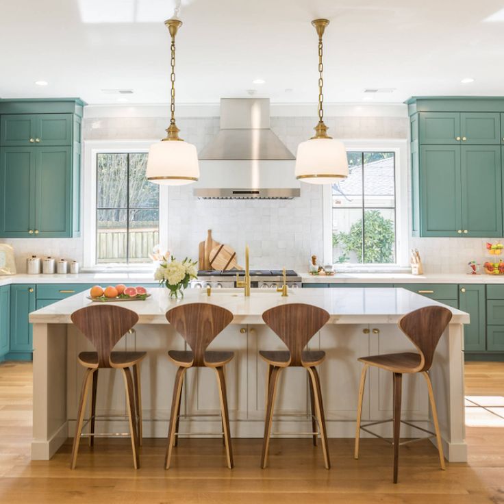 three wooden chairs sit at the center of a kitchen island