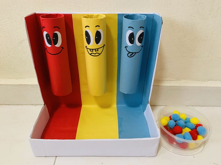 four different colored candy sticks with faces on them next to a bowl of candies