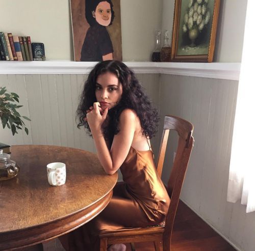 a woman sitting at a wooden table with a coffee cup in front of her face