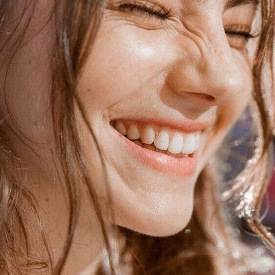 a close up of a woman smiling and holding a cell phone