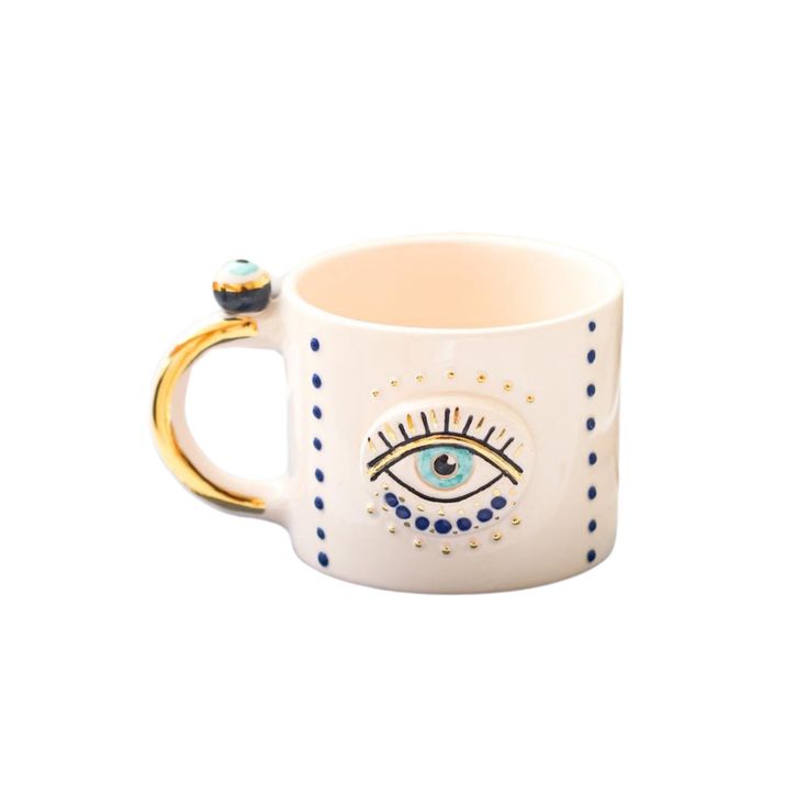 a coffee mug with an eye on the front and gold rimmings, sitting against a white background