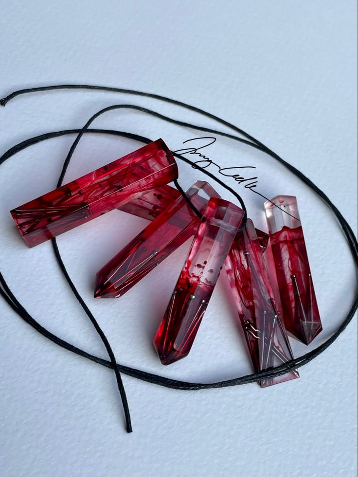 four red glass beads on a black cord