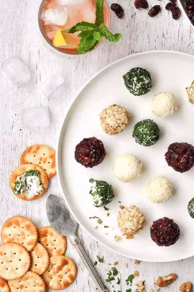 a white plate topped with cheese balls next to crackers and cranberry sauce