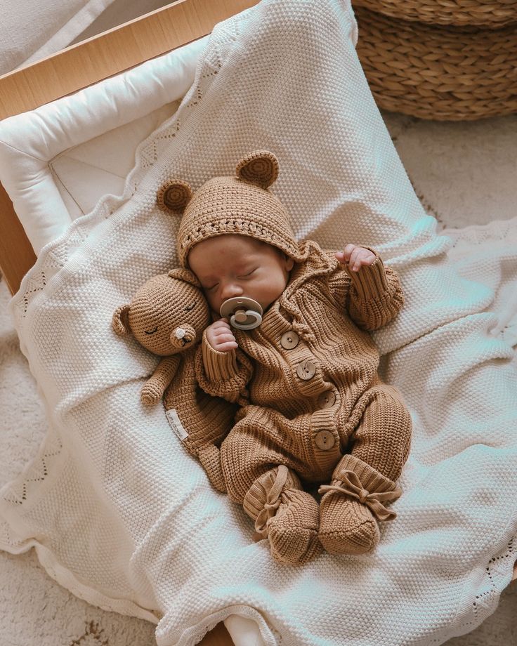 a baby in a bear suit sleeping on a bed