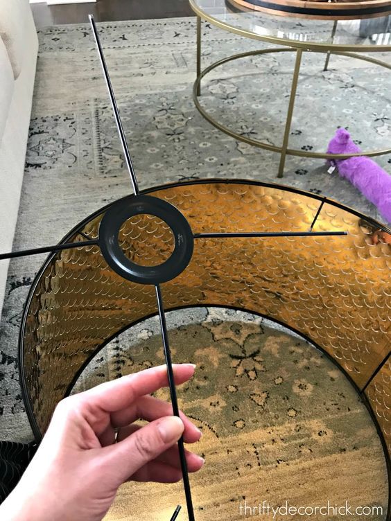 a hand holding a black object on top of a round glass table with metal legs