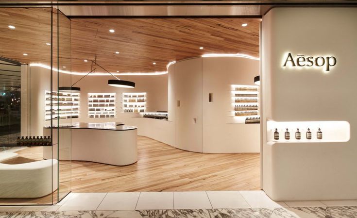 an aesop store with wooden floors and white walls, lighted by recessed lights