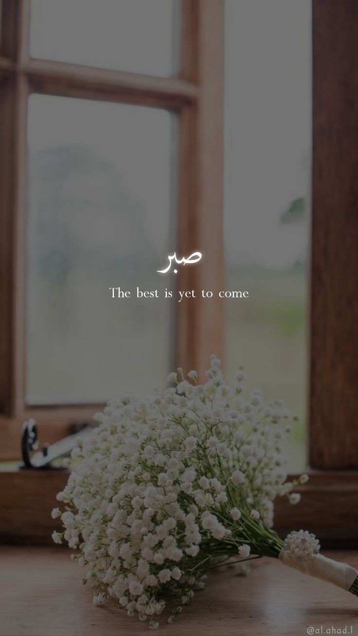 a bouquet of white flowers sitting on top of a wooden table next to a window