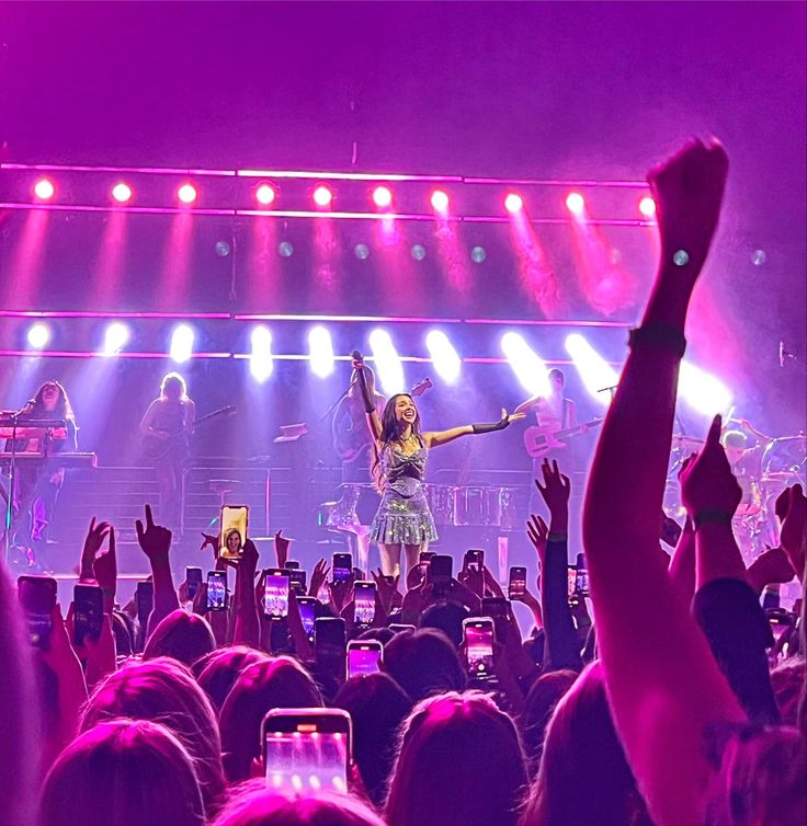 a woman standing on top of a stage with her arms in the air and hands up