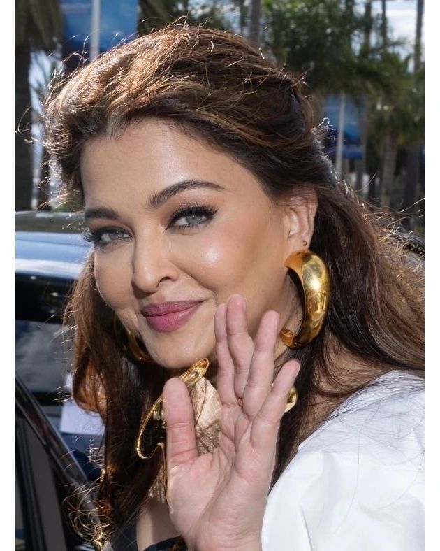 a woman with large gold hoop earrings on her neck and hand in front of her face