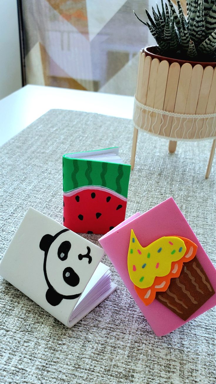 four small magnets are sitting on a table next to a potted plant and some books