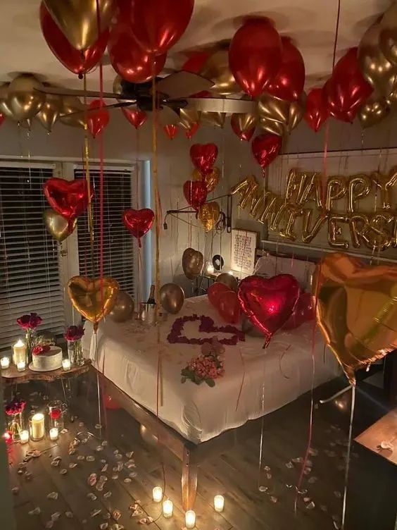 a bedroom decorated for valentine's day with balloons and candles