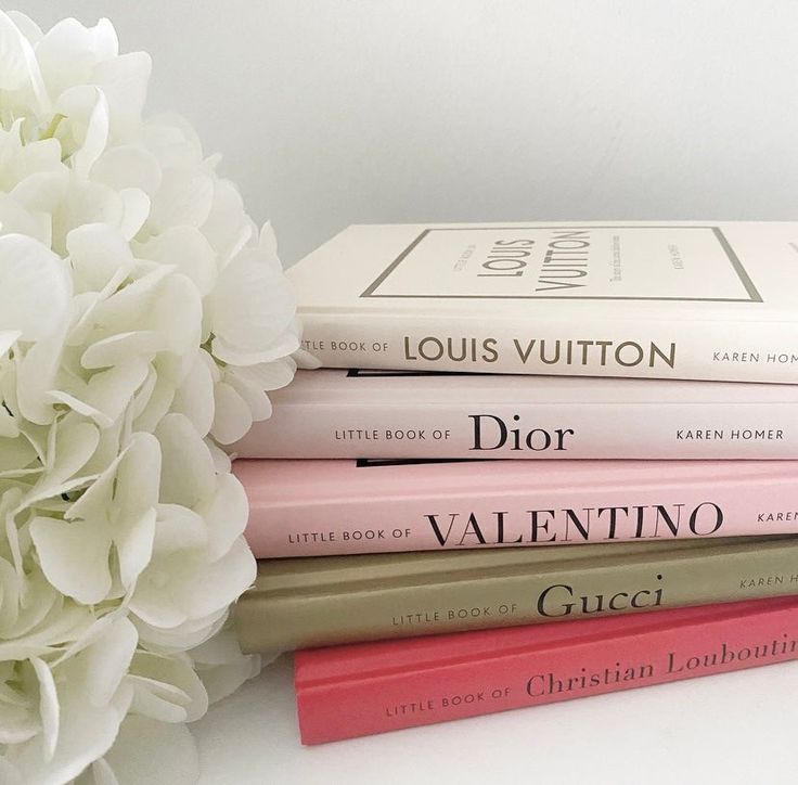 three books stacked on top of each other next to a bouquet of flowers and a white hydrangea