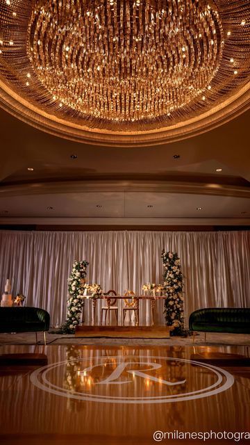 a large chandelier hanging from the ceiling in a room with couches and tables