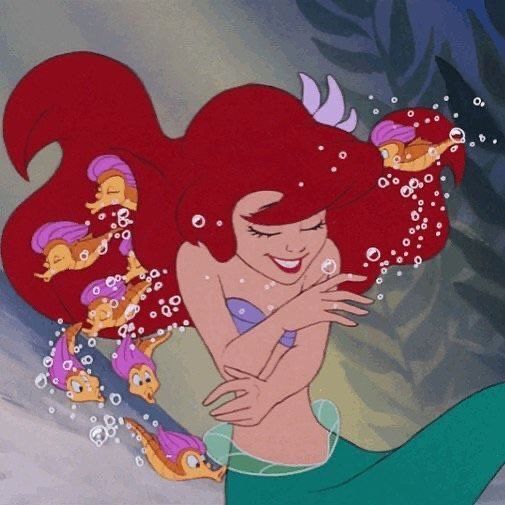 ariel from the little mermaid with her hair blowing in the wind and other fish around her