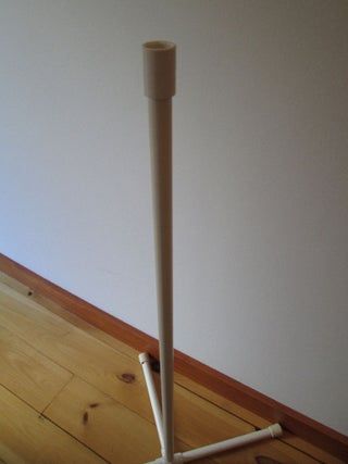 a white pole is on the floor in front of a wall and wood flooring