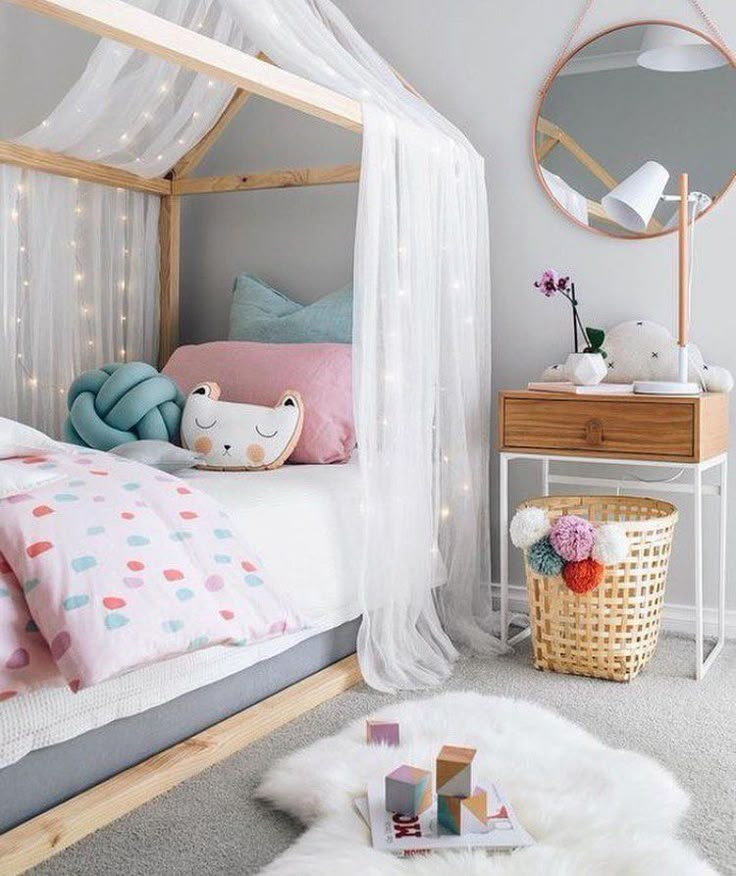 a bedroom with a white canopy bed, pink and blue decor and pillows on the floor