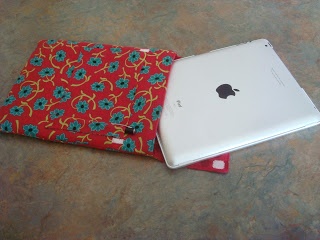 an apple ipad with a red flowered case sitting on the floor next to it