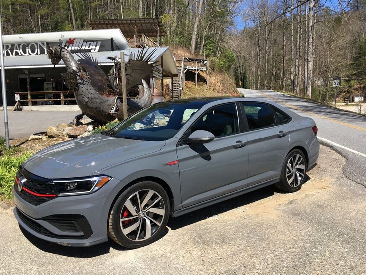 a gray car is parked on the side of the road in front of a store