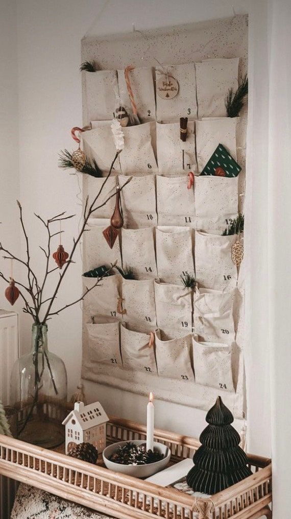 there is a christmas tree in front of a wall hanging with bags on it and a candle