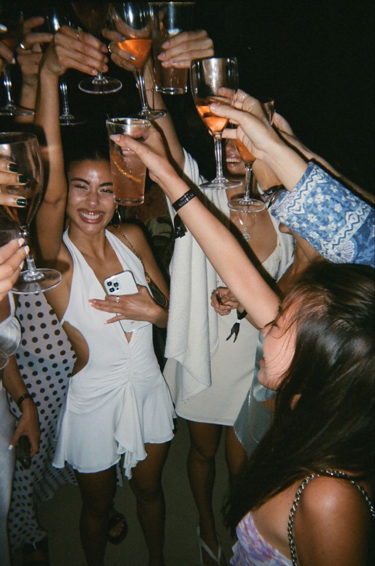 a group of people holding up wine glasses in front of each other at a party