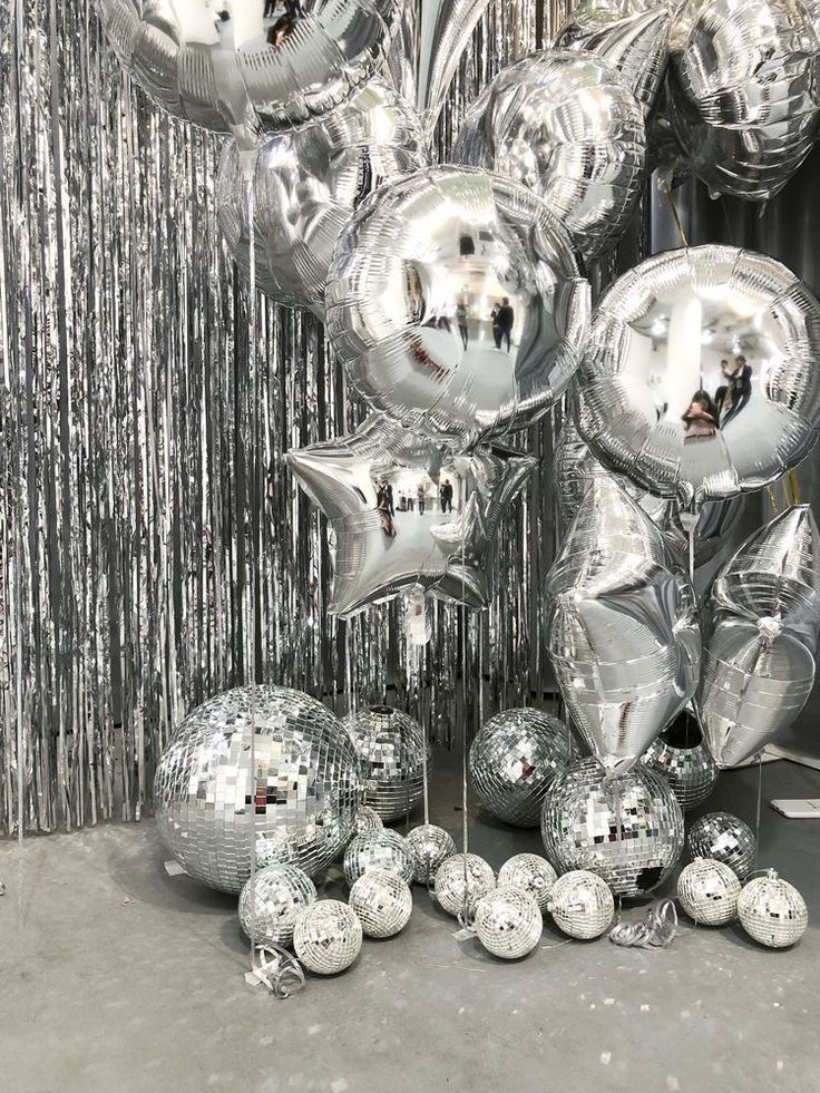 silver balloons and confetti balls are on the floor