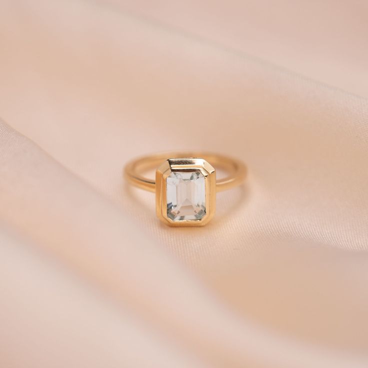 A stunning ring that stands out with its hand-selected crystal blue Aquamarine hues. Set in a timeless setting, this ring will stand the test of time and be passed down for generations to come. 14k Solid Gold and ethically-sourced Genuine Aquamarine Available in 14k Yellow Gold or 14k White Gold Available in sizes 3, 4, 5, 6, 7, and 8 Due to the handmade nature of this ring, please allow 1 - 3 weeks for processing. Timeless Emerald Ring With Bezel Setting For Wedding, Timeless Blue Topaz Ring Perfect As Gift, Timeless Blue Topaz Ring For Gift, Timeless Emerald Wedding Ring With Bezel Setting, Timeless Blue Topaz Ring As Gift, Heirloom Emerald Cut Solitaire Birthstone Ring, Timeless Blue Topaz Ring, 14k Gold Emerald Cut Solitaire Birthstone Ring, 14k Gold Emerald Cut Promise Ring