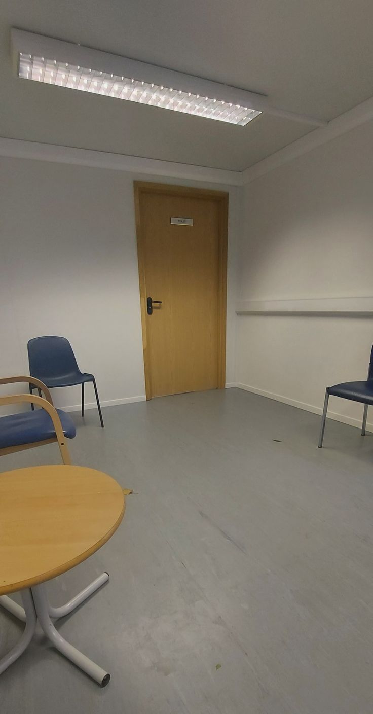 an empty room with two chairs and a table in the middle is seen from across the room