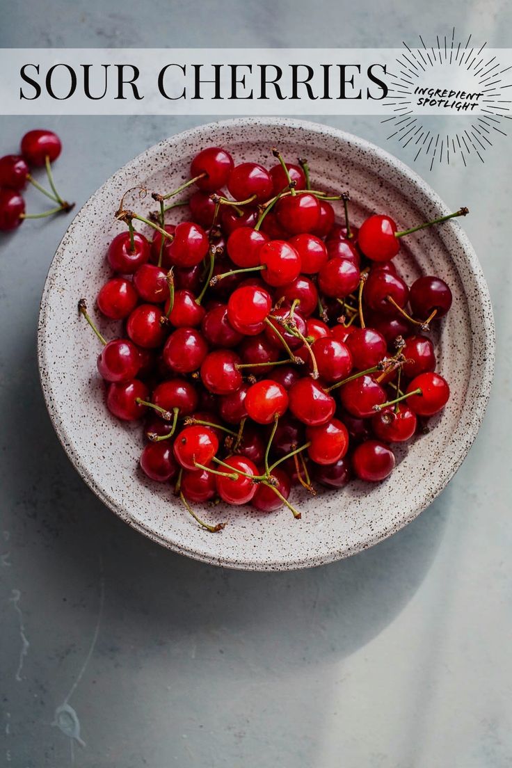 a bowl filled with cherries on top of a table