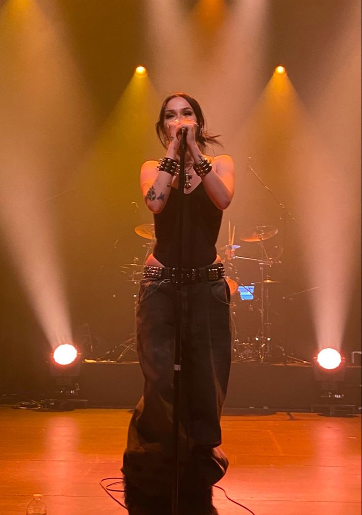 a woman standing on top of a stage with her hands in the air while holding a microphone