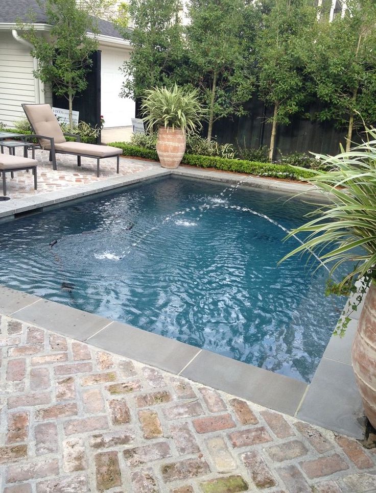 a small pool in the middle of a patio with chairs around it and a large potted plant