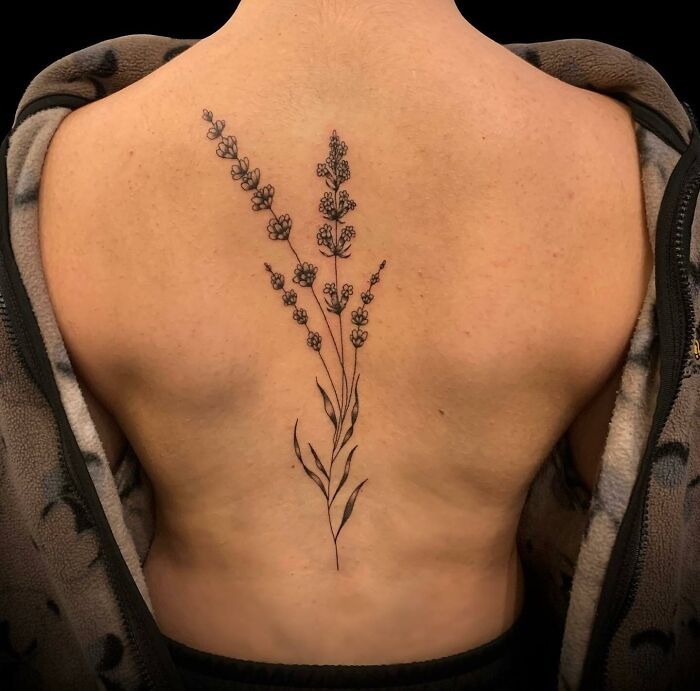 the back of a woman's upper body with lavender flowers on her left side