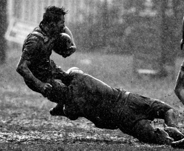 a rugby player dives for the ball as another tries to block it from him