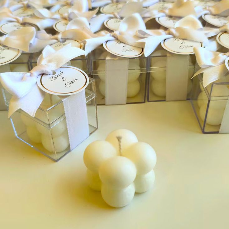 several small boxes filled with white candles and bows on top of each box are wrapped in ribbon