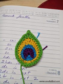 a crocheted brooch sits on top of an open notebook with writing underneath