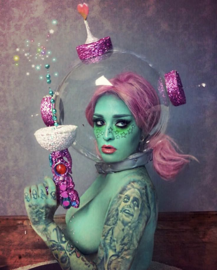 a woman with pink hair and green makeup holding a glass ball in her hands, surrounded by other objects