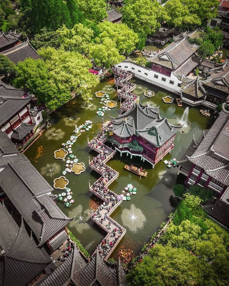 an aerial view of some buildings in the middle of a pond with people around it