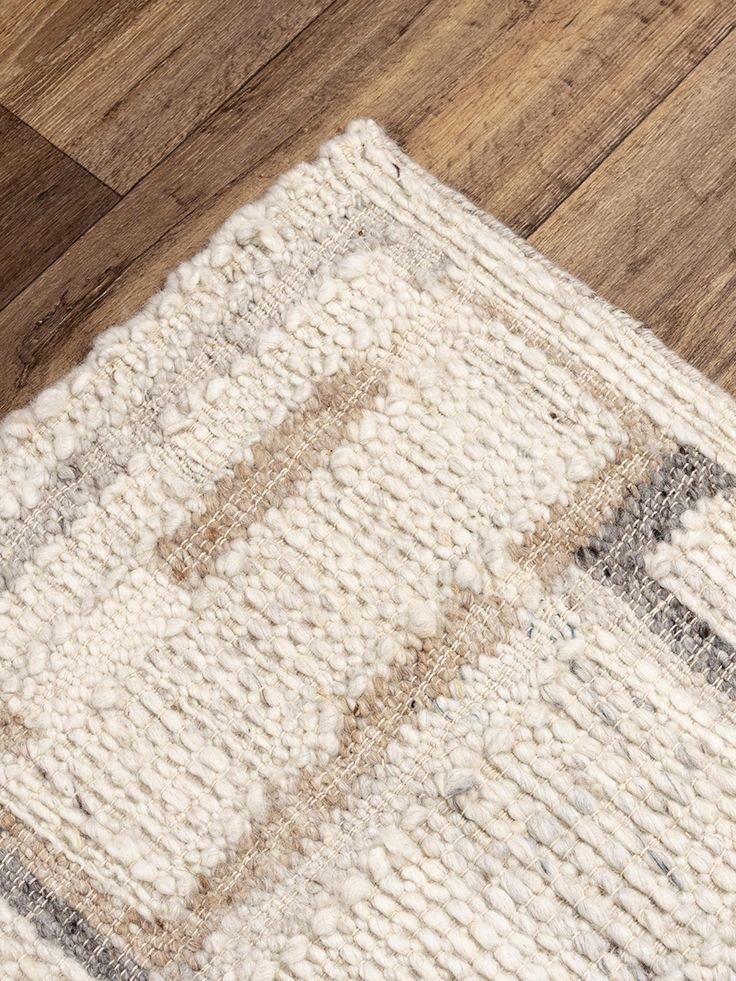 an area rug on the floor with wooden floors and wood planks in the background