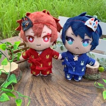 two small dolls sitting on top of a wooden table next to plants and grass in the background