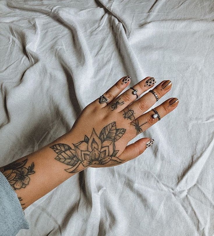 a woman's hand with tattoos on it laying on a white sheet covered bed