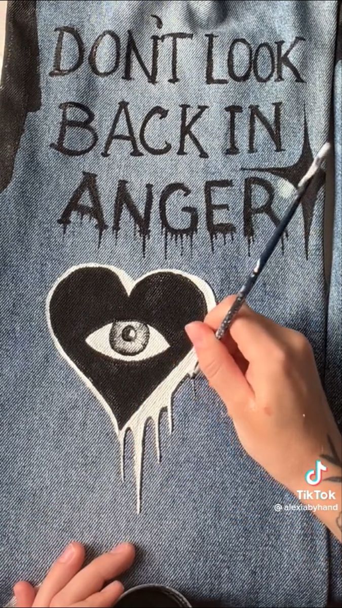 someone is drawing an eye on a pair of jeans with the words, don't look back in anger