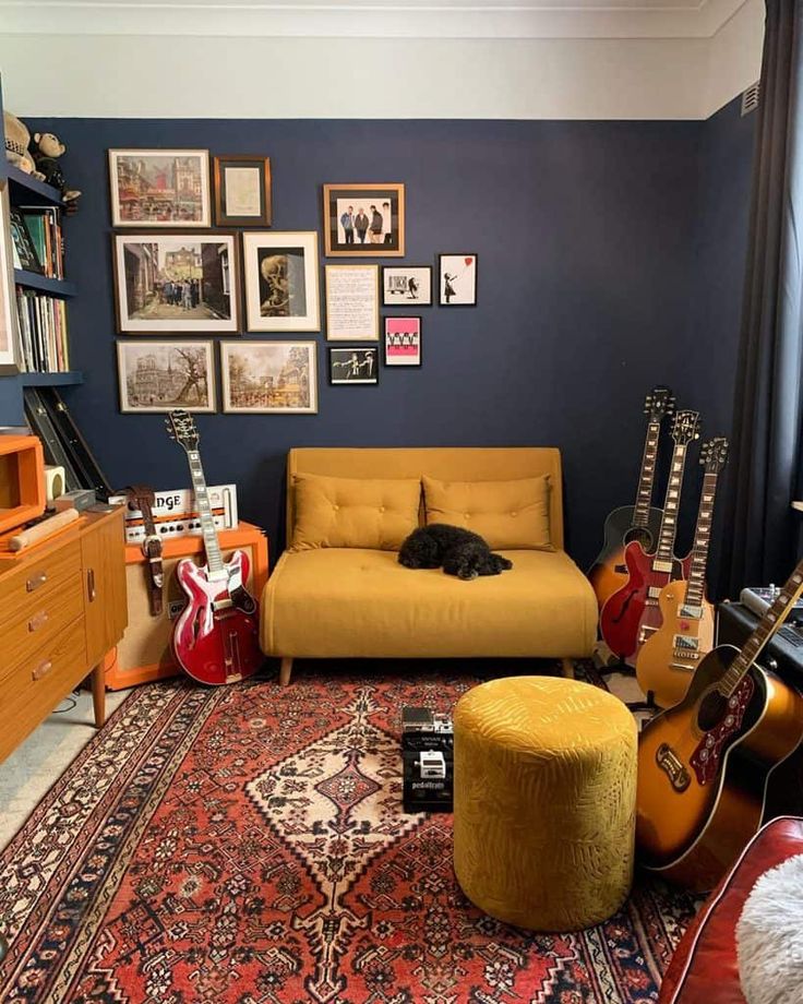 a living room filled with guitars and a yellow couch in front of a blue wall