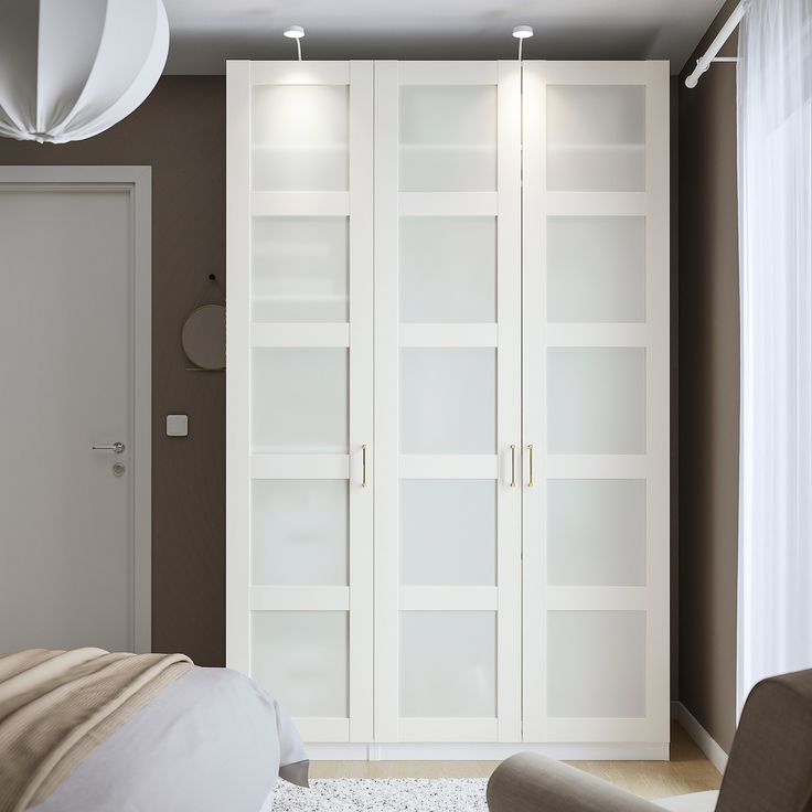 a bedroom with a bed, chair and white bookcases