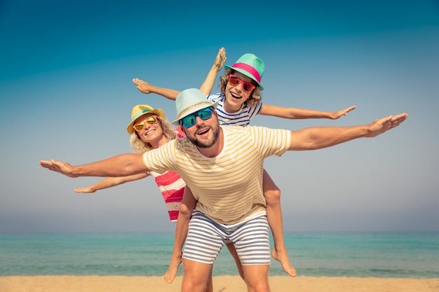 three people are on the beach with their arms in the air and one person is holding another