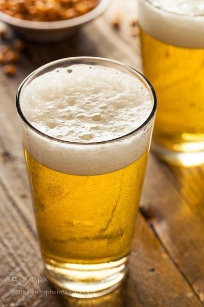 two glasses filled with beer sitting on top of a wooden table