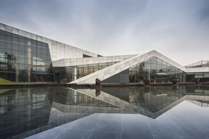 the exterior of a building with glass walls and water reflecting it's reflection in the pool