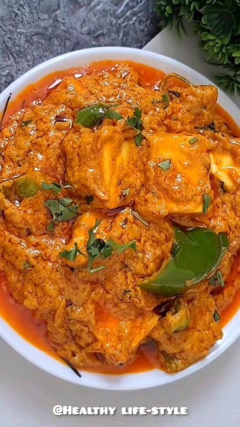 a white bowl filled with meat and vegetables covered in sauce on top of a table