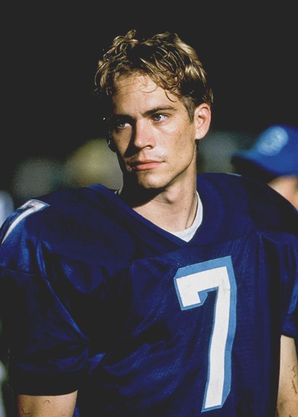 a young man wearing a football uniform standing in the dark