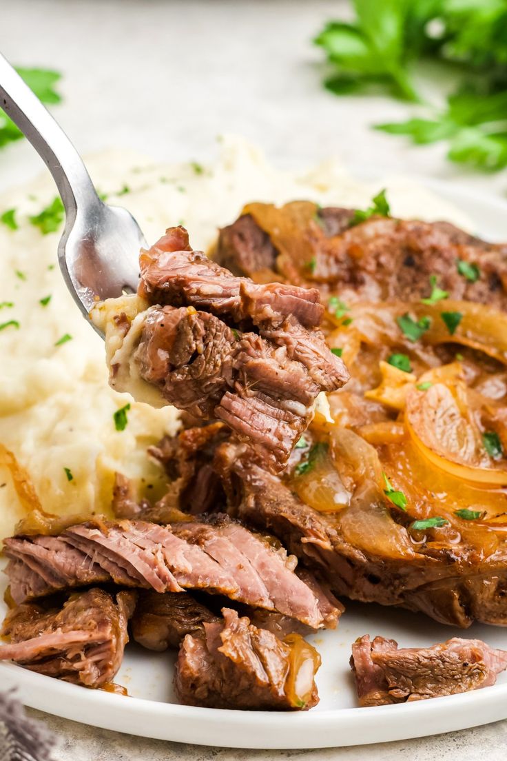 a white plate topped with meat and mashed potatoes