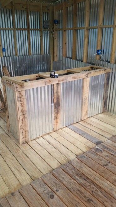 an outdoor bar made out of metal and wooden planks on a deck in the middle of a building